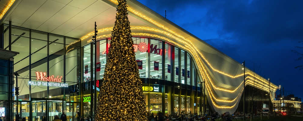 Grote gedecoreerde kerstboom en gevelverlichting winkelcentrum